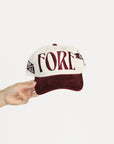Cap with 'FORE' text held by a hand on a white background