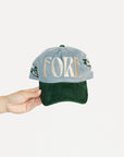 Cap with 'FORE' text held by a hand on a light gray background