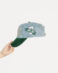 Cap with 'FORE' text held by a hand on a light gray background