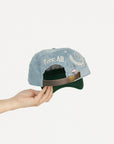 Cap with 'FORE' text held by a hand on a light gray background