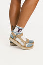 Person wearing sandals and socks with a visible brand logo on a white background