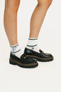 Black loafers with white socks featuring green and blue text on a white background