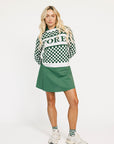 Woman wearing a green and white checkered Fore Sweater with 'FORE' text on a white background