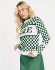Woman wearing a green and white checkered Fore Sweater with 'FORE' text on a white background