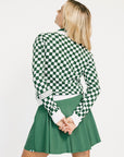 Woman wearing a green and white checkered Fore Sweater with 'FORE' text on a white background