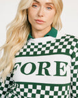 Woman wearing a green and white checkered Fore Sweater with 'FORE' text on a white background