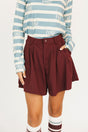 Person wearing a smoke blue Lottie Mock Neck and merlot Eleanor shorts on a plain background