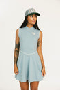 Woman wearing a light blue sleeveless dress with a logo and a matching cap on a white background