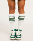 Person wearing green and white sneakers with matching socks on a light background