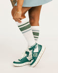 Person wearing green and white sneakers with matching socks on a light background