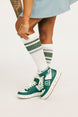 Person wearing green and white sneakers with matching socks on a light background