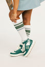 Person wearing green and white sneakers with matching socks on a light background