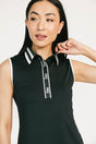 Woman wearing a black sleeveless Moore Polo with white collar and text details on a plain background