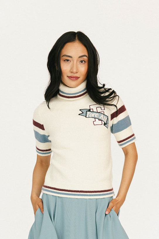 Woman wearing a striped sweater, light blue skirt, and white sneakers on a white background