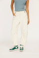 Person wearing white pants and green sneakers on a plain background