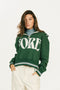 Woman wearing a green sweatshirt with 'FORE' text on a white background