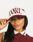 Woman wearing a cap with 'FORE' branding on a white background
