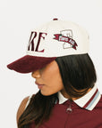 Woman wearing a cap with 'FORE' branding on a white background