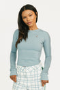 Woman wearing a smoke blue Marie long-sleeve top and plaid pants on a white background