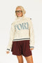 Person wearing a cream hoodie with 'FORE' text and maroon shorts on a white background