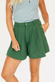 Person wearing a smoke blue sleeveless Annie Polo and a green Eleanor short on a plain background