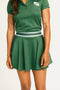 Person wearing a green Brooklyn skirt and polo on a white background. Featuring built in shorties and a Fore All logo on the front.