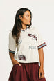 Woman wearing an angora Fore All Dillon Polo with various logos on a plain background