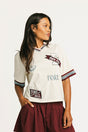 Woman wearing an angora Fore All Dillon Polo with various logos on a plain background