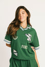 Woman wearing a green Fore All Dillon Polo with visible branding on a plain background