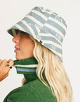 Person wearing the Fore All Austi Bucket Hat with a green sweater with a logo