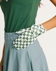 Person wearing a green and white checkered glove on a plain background