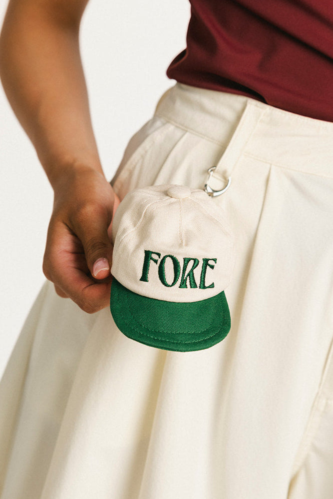 Person holding a cap with &#39;FORE&#39; printed on it against a white background