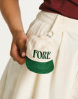 Person holding a cap with 'FORE' printed on it against a white background