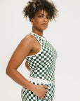 A woman wearing a green checkered tank top with a built-in bra, designed for golfing or casual wear.