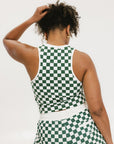 A woman wearing a green checkered tank top with a built-in bra, designed for golfing or casual wear.