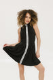 A woman models a black sleeveless dress with a zipper that extends from the top to the bottom. The dress has a relaxed fit and she is wearing it with sneakers.