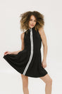 A woman models a black sleeveless dress with a zipper that extends from the top to the bottom. The dress has a relaxed fit and she is wearing it with sneakers.