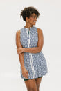 A model wearing a sleeveless blue and white geometric patterned dress with a zipper at the top, suitable for golf.