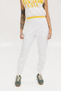 A person wearing white athletic pants and a white t-shirt with yellow details, standing against a white background.