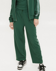 Person wearing a green tracksuit with white stripes on a white background