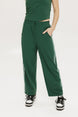 A person standing wearing green Bronson pants with a drawstring waist, green top, and black and white sneakers.