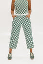 A pair of green checkered pants with a relaxed fit and pockets, worn by a model in a matching checkered top and sneakers.