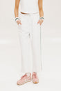 A pair of white Bronson pants with a subtle stripe detail on the side, paired with a white top and pink sneakers.