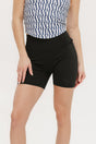 A person wearing black mid-thigh length shorts, called Biddy Shorties, with a blue and white geometric patterned top.