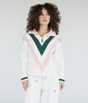 A woman wearing a white sweatshirt with pink and green geometric patterns and a quarter-zip design.