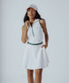 A woman wearing a white ribbed sleeveless golf dress with a high collar and a full front zipper.