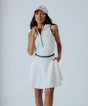 A woman wearing a white ribbed sleeveless golf dress with a high collar and a full front zipper.