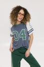 A woman wearing a blue and white striped t-shirt with the number '04' on it, paired with green pants.