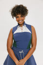 A woman wearing a sleeveless colorblocked mock neck tank top in blue and green with mesh accents and a flat drawstring cord.