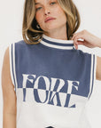 A woman wearing a sleeveless mock-neck sweater with 'FORE' text in blue and white colors.